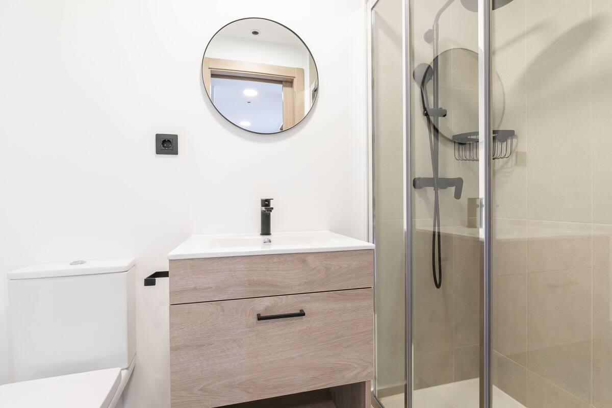 A modern bathroom with a toilet, a sink with a mirror, and a glass-enclosed shower area.