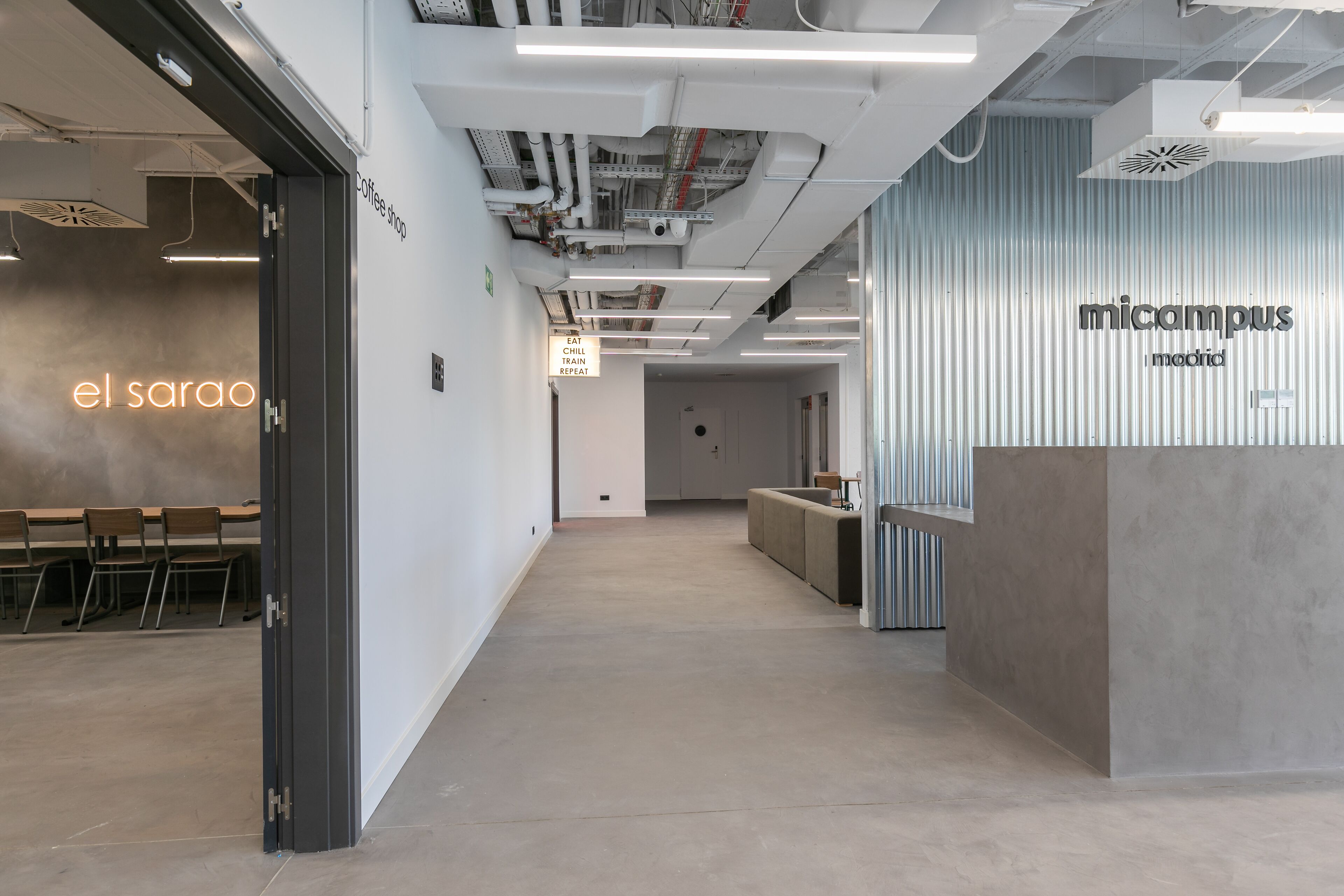 Un espacio de oficina moderno con una zona de recepción que indica 'micampus madrid'.