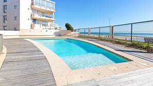 A modern building with a pool and a wooden deck.