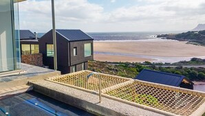 Ein modernes Gebäude mit Poolbereich und Blick auf einen Strand.