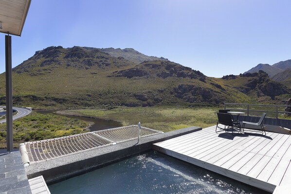Ein Pool mit Blick auf Berge, eine Holzterrasse und Gartenmöbel.