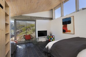 Ein modernes Schlafzimmer mit Bett, Fernseher und einem Fenster mit Jalousien.