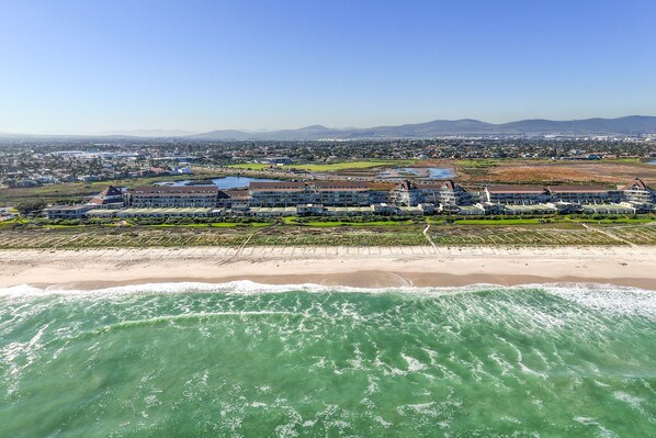 A coastal hotel with multiple buildings, a beachfront, and a view of the ocean.