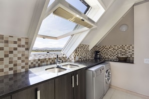 A kitchen with a skylight, two sinks, a coffee maker, and a washing machine. - Dolphin Beach H301 - One Bedroom Apartment, Sleeps 2 (Cape Town)