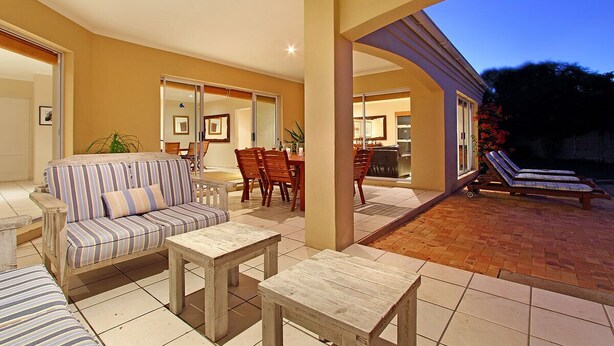 An outdoor patio area with a sofa, dining table, chairs, and a lounge chair. - Durham Close 31 - Four Bedroom House, Sleeps 8 (Cape Town)