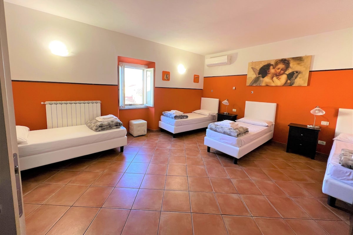 Una habitación con dos camas, una ventana, un radiador y un cuadro en la pared.