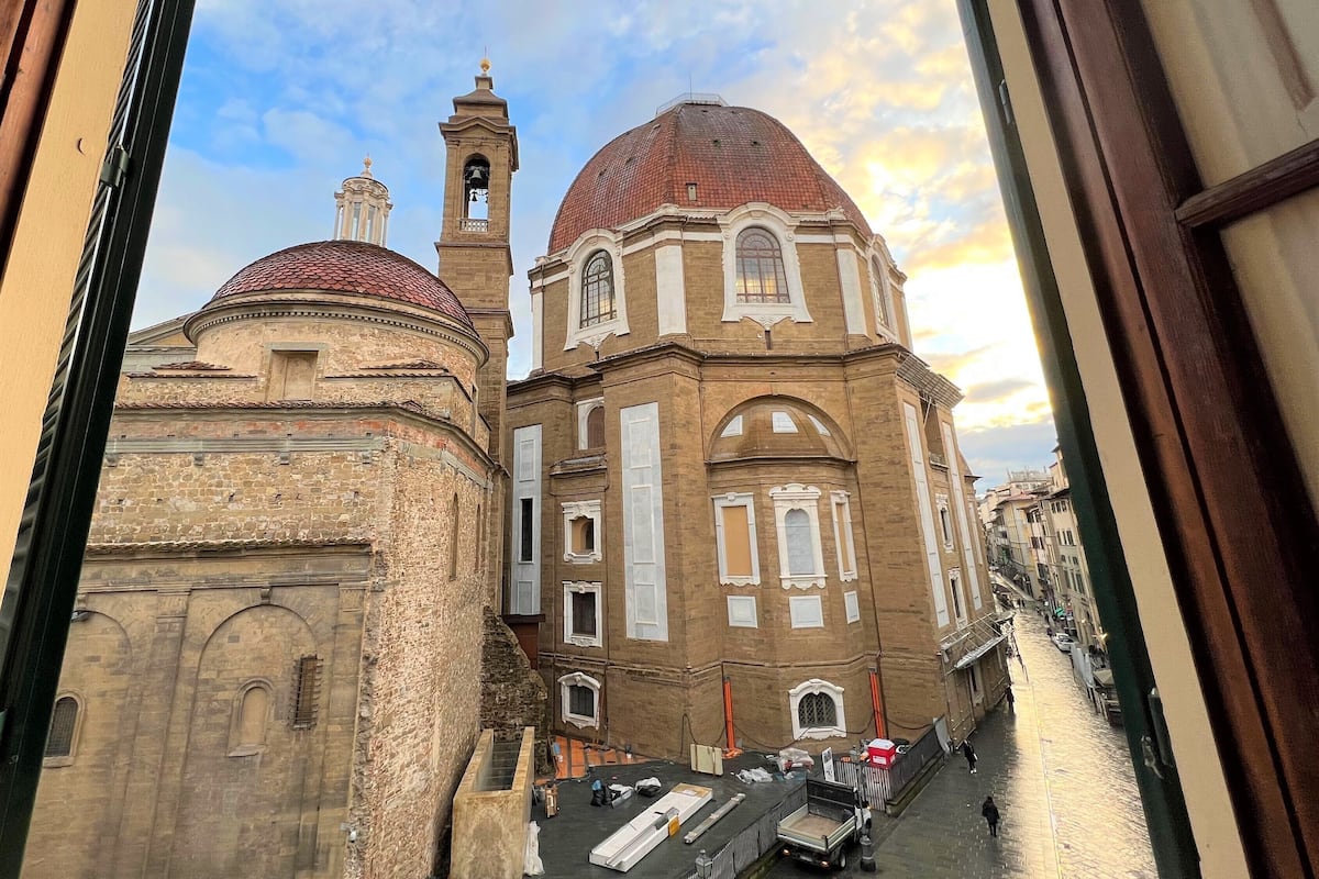 Un edificio histórico con una torre de campanas y una cúpula, visto desde una ventana.