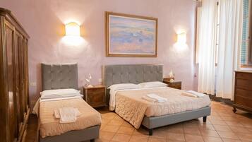 Quarto de hotel com duas camas, um quadro grande na parede e duas luminárias fixadas na parede.