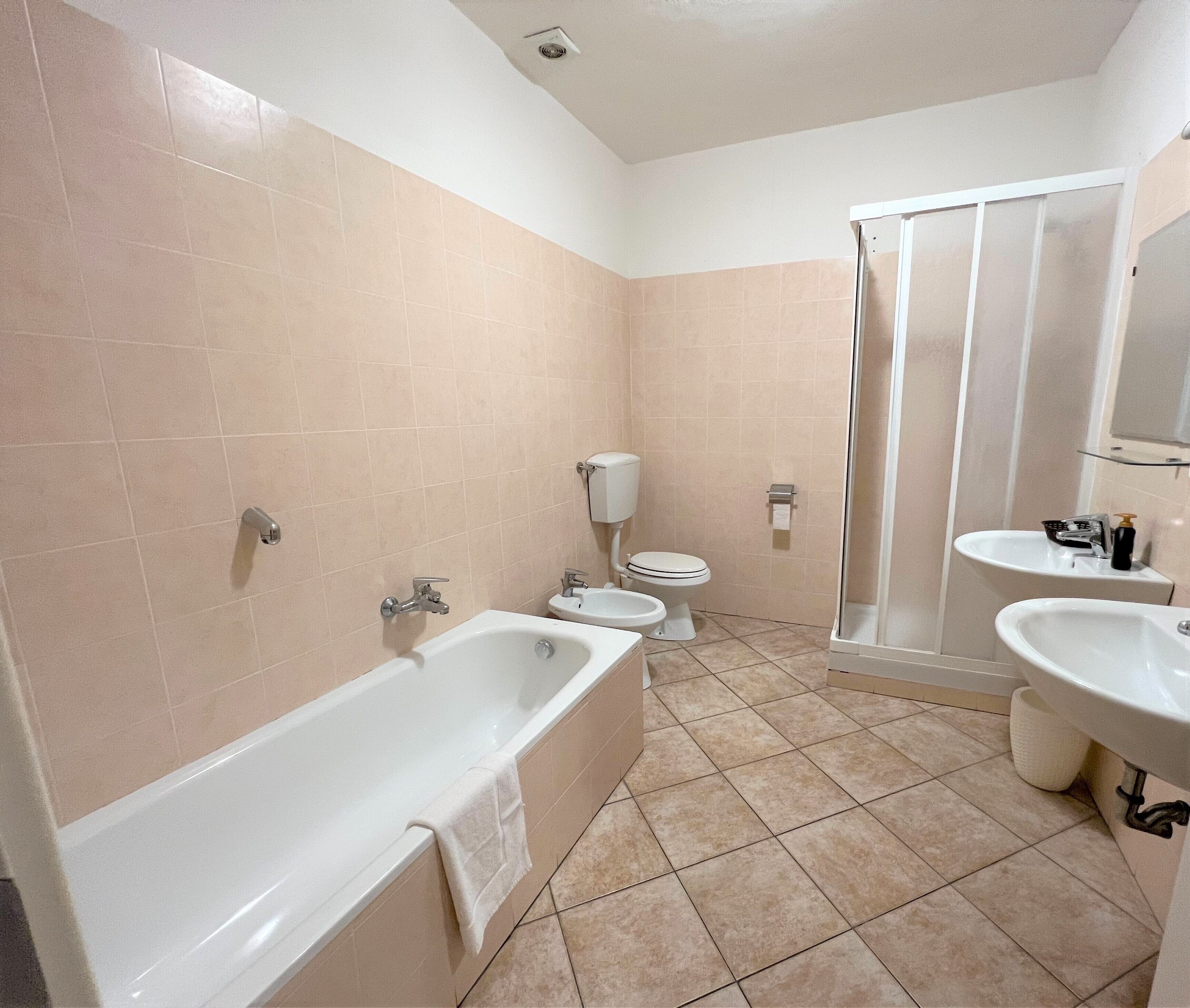 Un baño con bañera, dos lavamanos, inodoro y ducha.