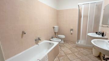 Un baño con bañera, dos lavamanos, inodoro y ducha.