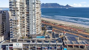 Un hotel moderno de gran altura con varios balcones con vistas a una playa y al océano.