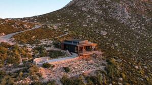 A modern house with a deck, surrounded by rocky terrain and sparse vegetation. - Klein-Hangklip - Two Bedroom House, Sleeps 4 (Cape Town)