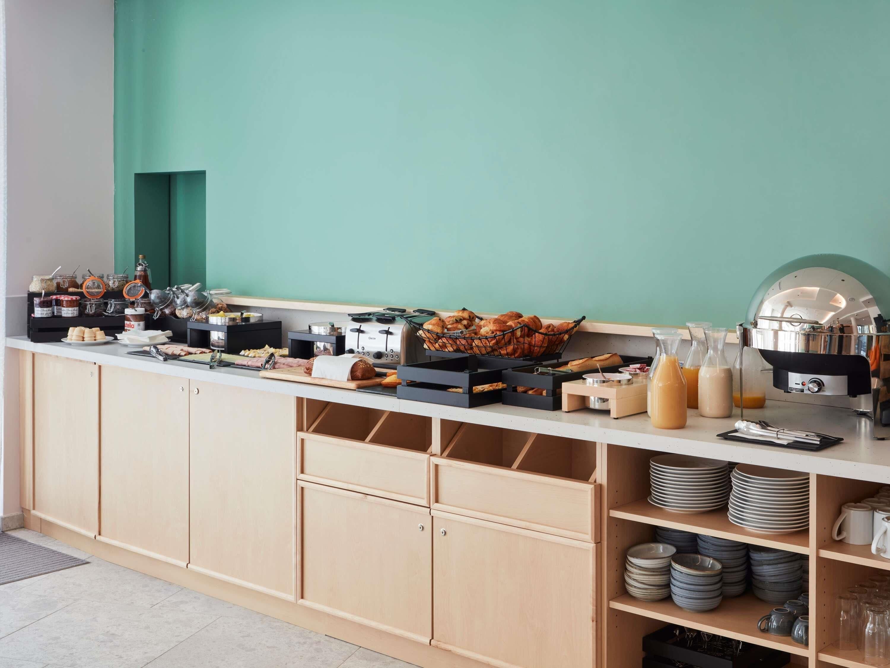 Un buffet proposant une variété de plats, une machine à café et un comptoir avec des ustensiles.