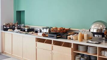 Un buffet proposant une variété de plats, une machine à café et un comptoir avec des ustensiles.
