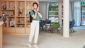 Ein modernes Bibliotheken-Interieur mit Holzbögen, einer Sitzecke mit bunten Stühlen und einer großen weißen Säule.