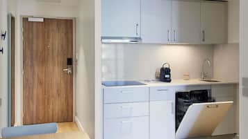A modern kitchen with white cabinets, a built-in dishwasher, and a coffee machine.