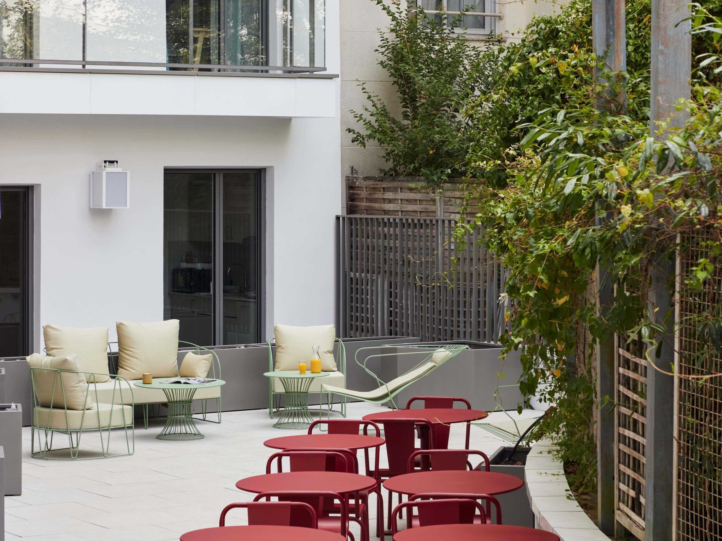 Un patio al aire libre con mobiliario, una hamaca y vistas de un edificio moderno.