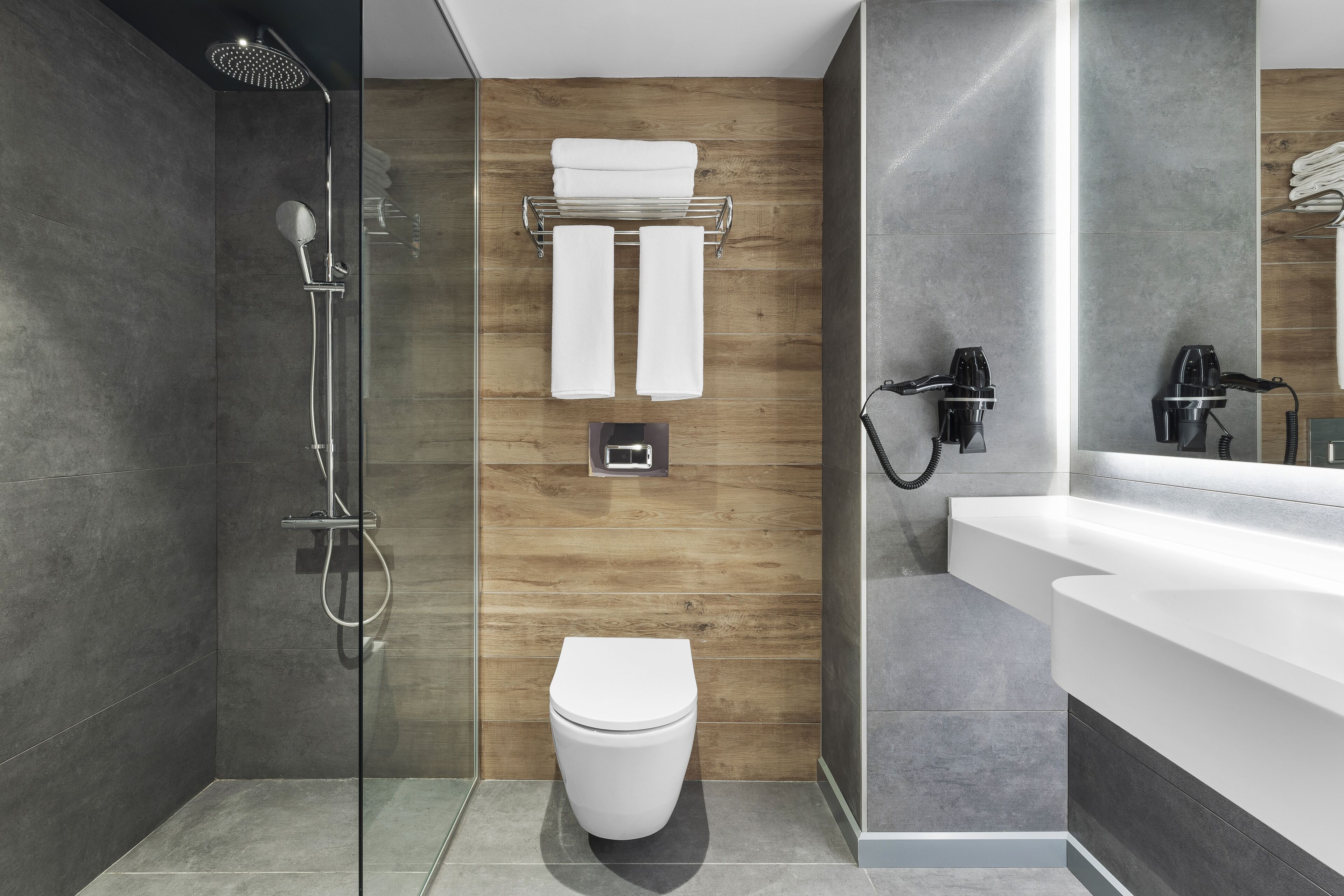 Ein modernes Badezimmer mit einer gläsernen Dusche, einer weißen Toilette und einer Wand mit Holzvertäfelung.