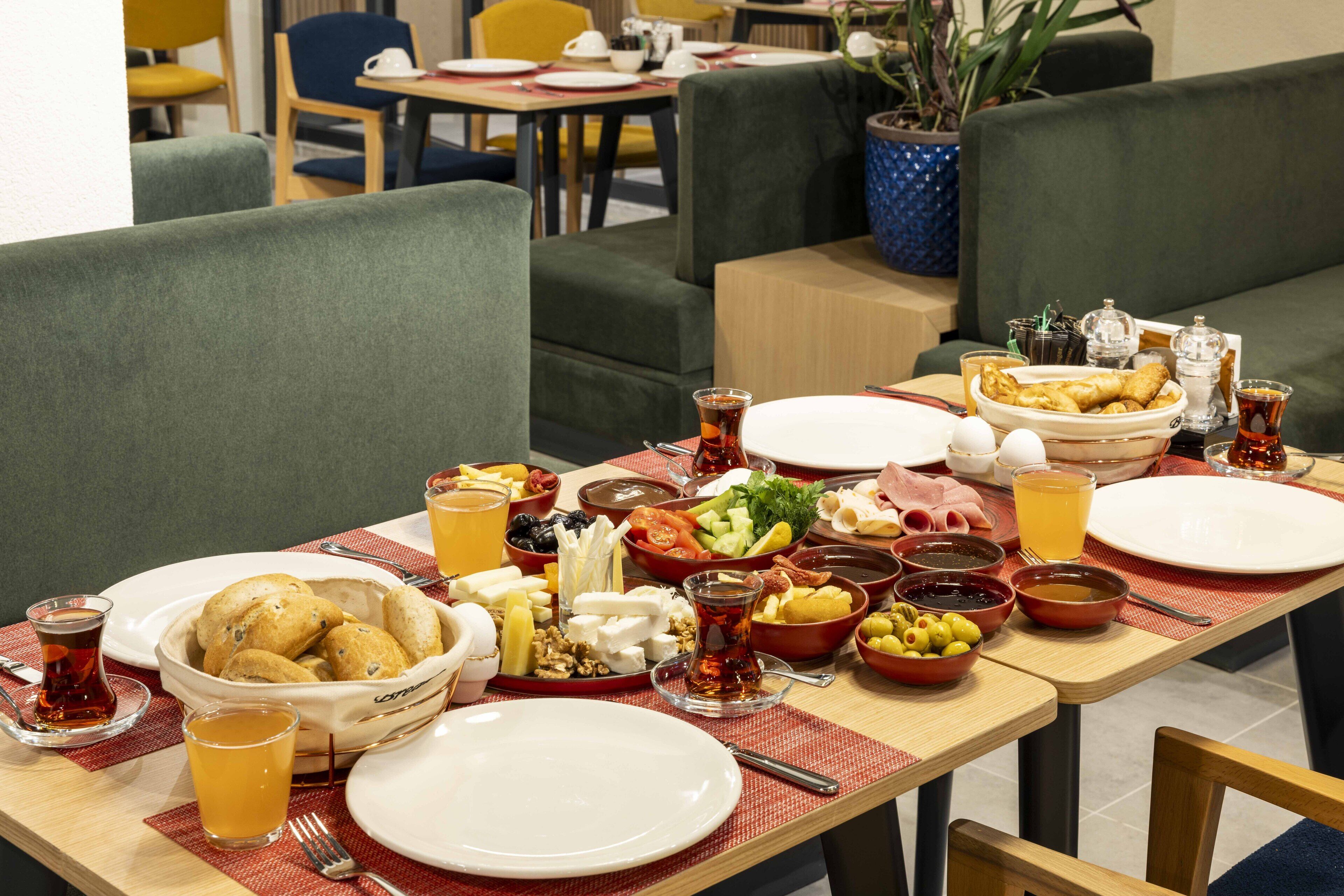Una mesa de comedor preparada con diversos platos, incluyendo pan, queso y verduras, en un restaurante.