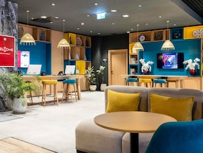 En modern hotellobby med en receptionsdisk, en sittgrupp och en tv.