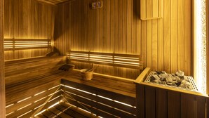 A wooden sauna with benches and benches, a wooden wall, and a wooden bench with a bucket and rocks. - ibis Istanbul Sisli (Istanbul)