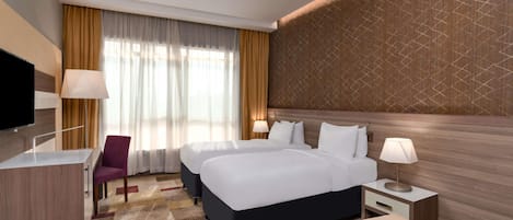 Una habitación de hotel con una cama grande, un escritorio, una silla y un televisor.
