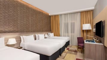 Hotelkamer met een groot bed, twee nachtkastjes, een bureau met stoel, een televisie en een behang met patroon.