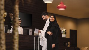 A reception area with wooden paneling, a reception desk, and two pendant lights. - Mercure Makkah Aziziah (Makkah)