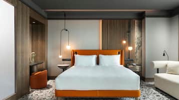 Una camera d'hotel moderna con un letto grande, un tavolino, una comodino, un divano e una lampada a parete.