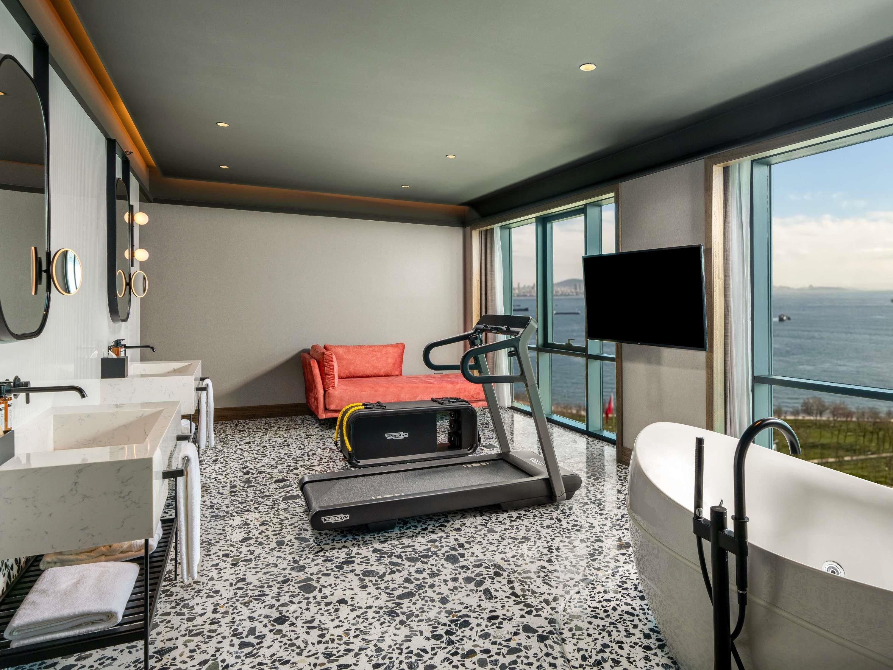 Un bagno moderno con una vasca da bagno grande, un tapis roulant e un divano.