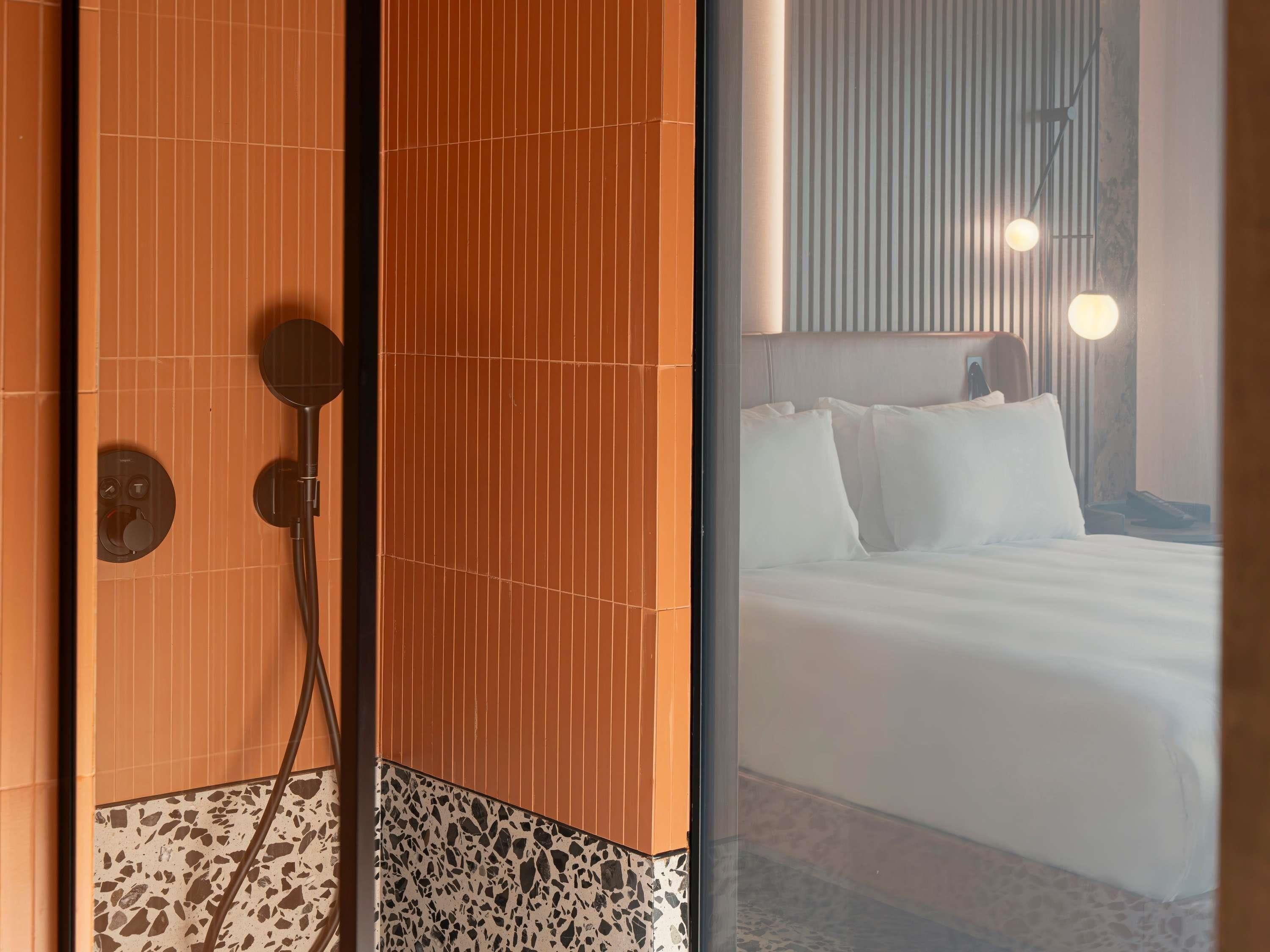 Un baño moderno con ducha, inodoro y lavamanos. El piso está cubierto de azulejos con un diseño moteado.