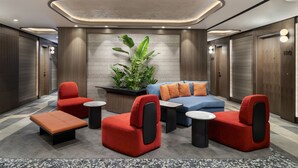 Un espace détente moderne avec un canapé bleu, des fauteuils rouges et une petite table.