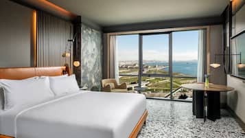 Una habitación de hotel con una cama grande, un área de estar con vistas y una mesa de comedor.