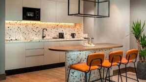 Une cuisine moderne dotée d’un îlot central, de tabourets de bar, d’un four à micro-ondes et d’une machine à café.