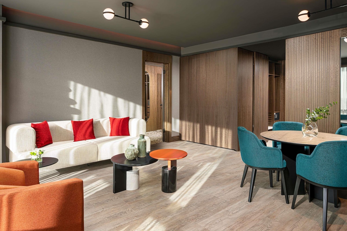 A modern living room with a sofa, coffee table, and dining area.