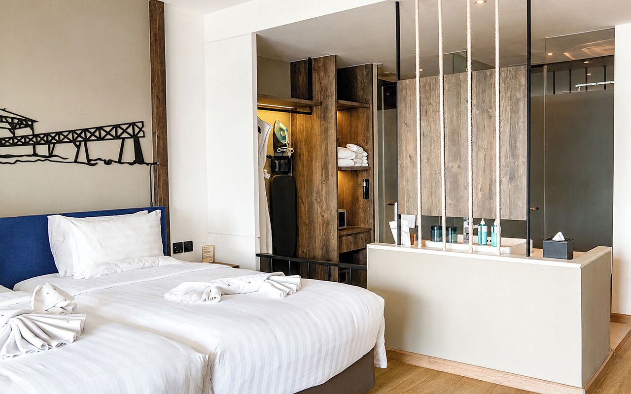 A hotel room with a bed, a desk, and a mirror.