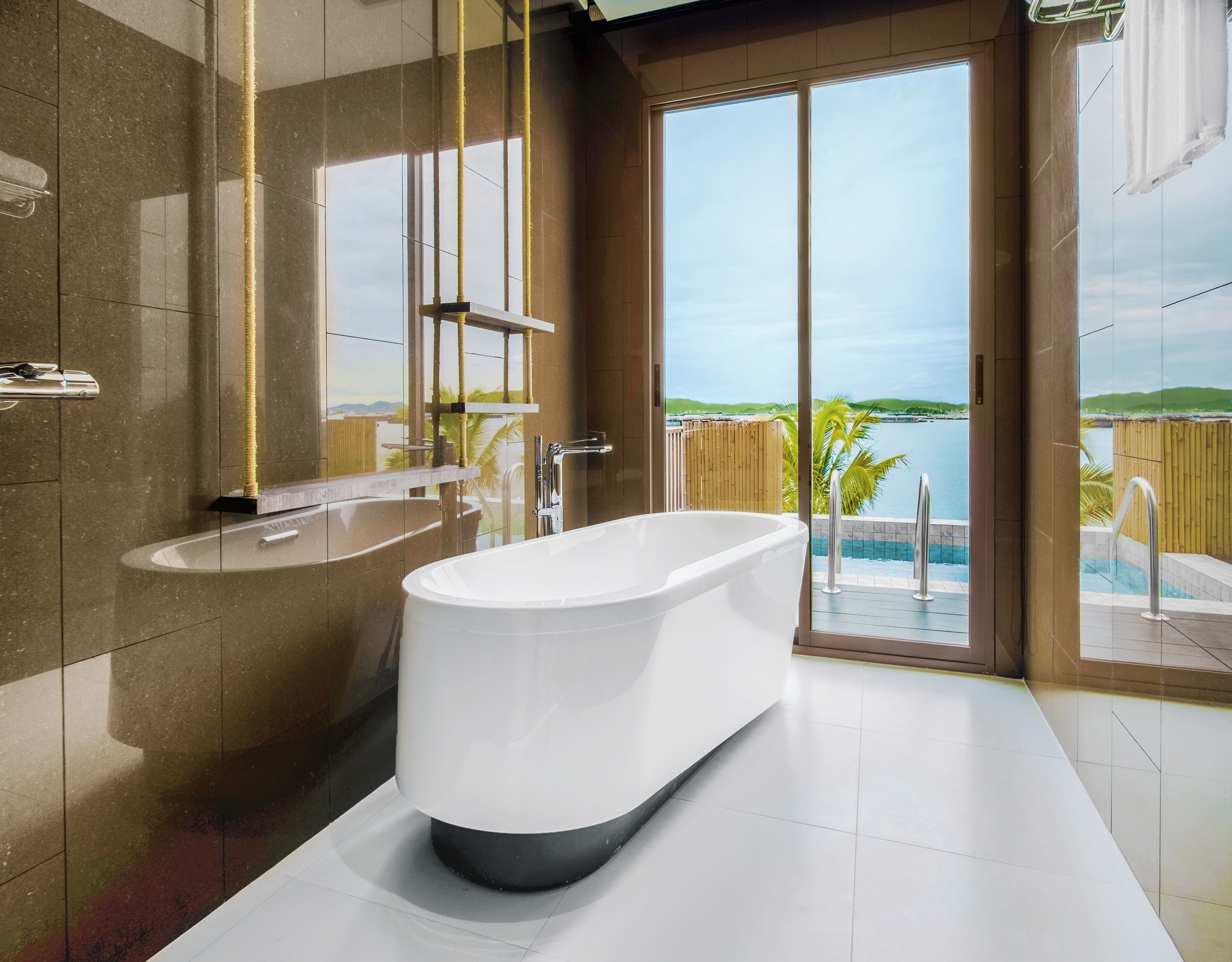 Un baño moderno con una bañera independiente, un espejo grande y vistas a una piscina y paisaje.