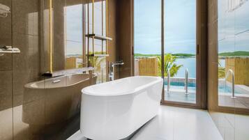 Un baño moderno con una bañera independiente, un espejo grande y vistas a una piscina y paisaje.