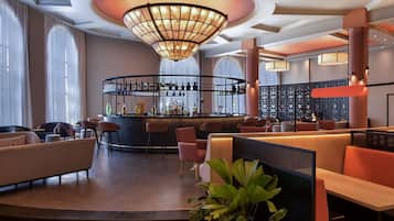 Un espace bar doté d’un comptoir incurvé, de tabourets de bar et d’un grand lustre.
