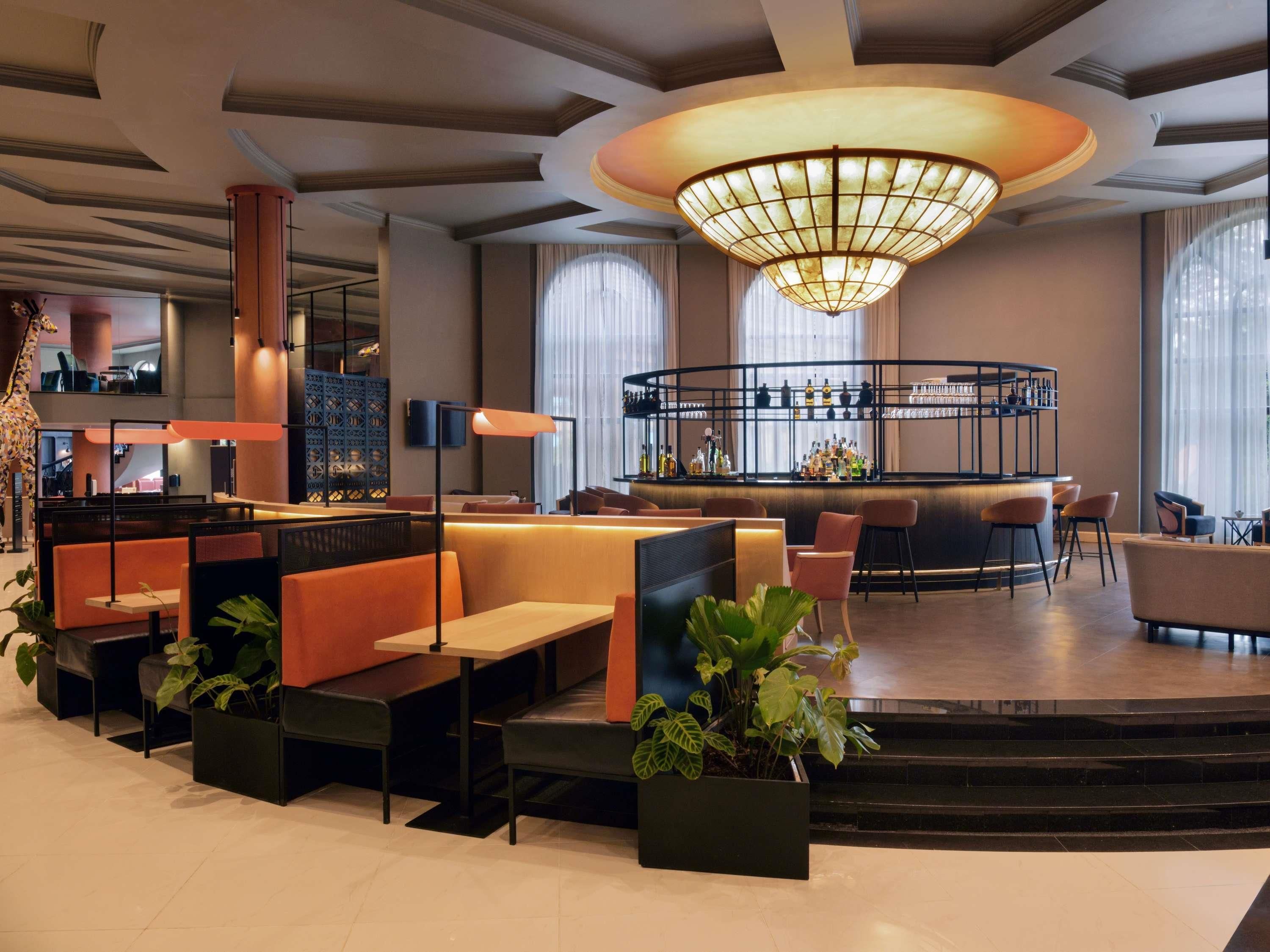 A modern bar area with seating and a large chandelier.