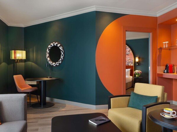 A modern hotel room with a round mirror, a desk with a lamp, a sofa, and a coffee table. - Pullman Nairobi Upper Hill (Nairobi)