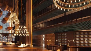Un hall d’entrée spacieux avec un plancher en bois, de grandes suspensions lumineuses, un comptoir de réception et un mur recouvert de porte-clés.