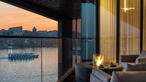Un intérieur moderne offrant une vue sur une rivière et sur le paysage urbain au coucher du soleil.