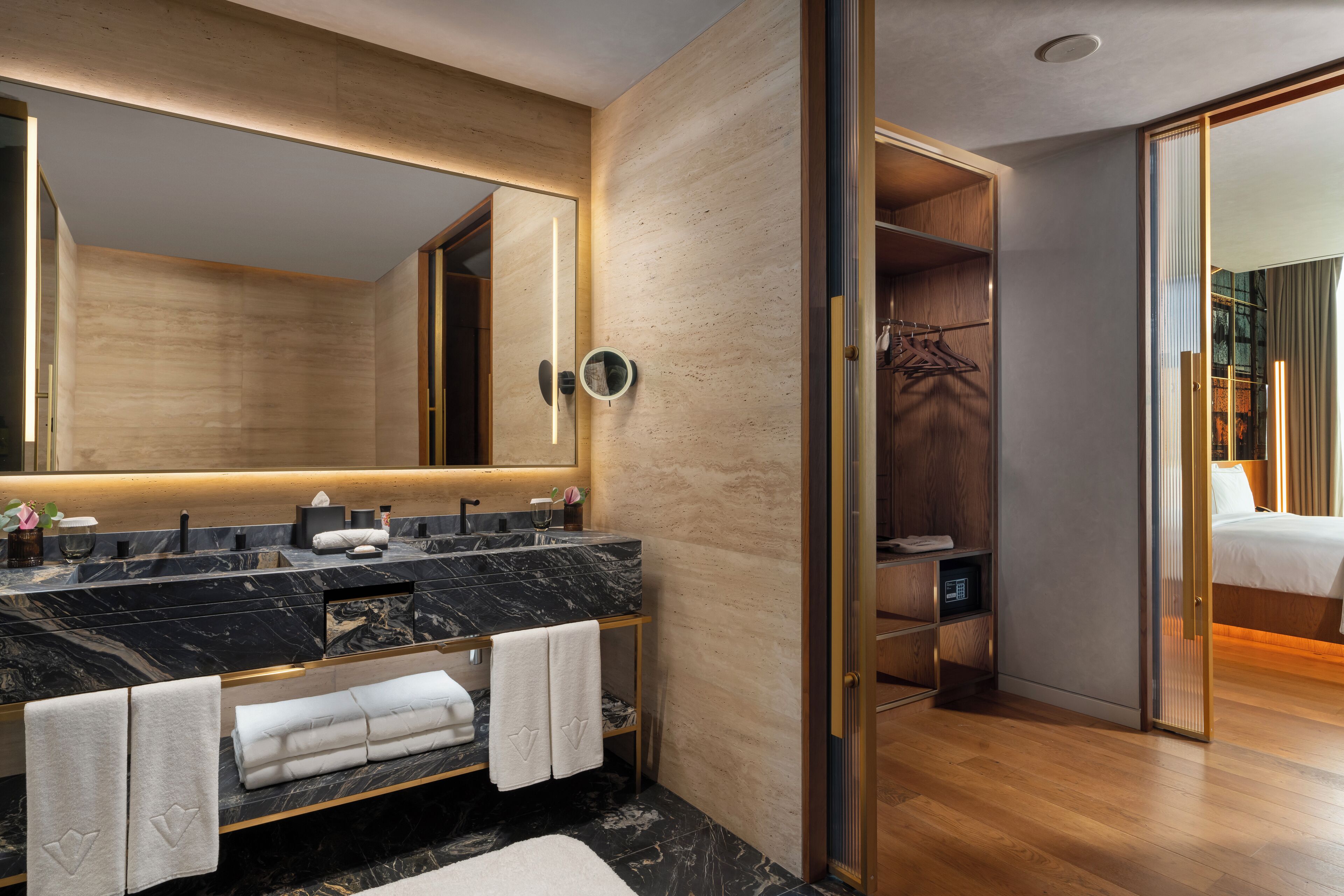 A modern bathroom with a large mirror, marble sink, and wooden vanity.