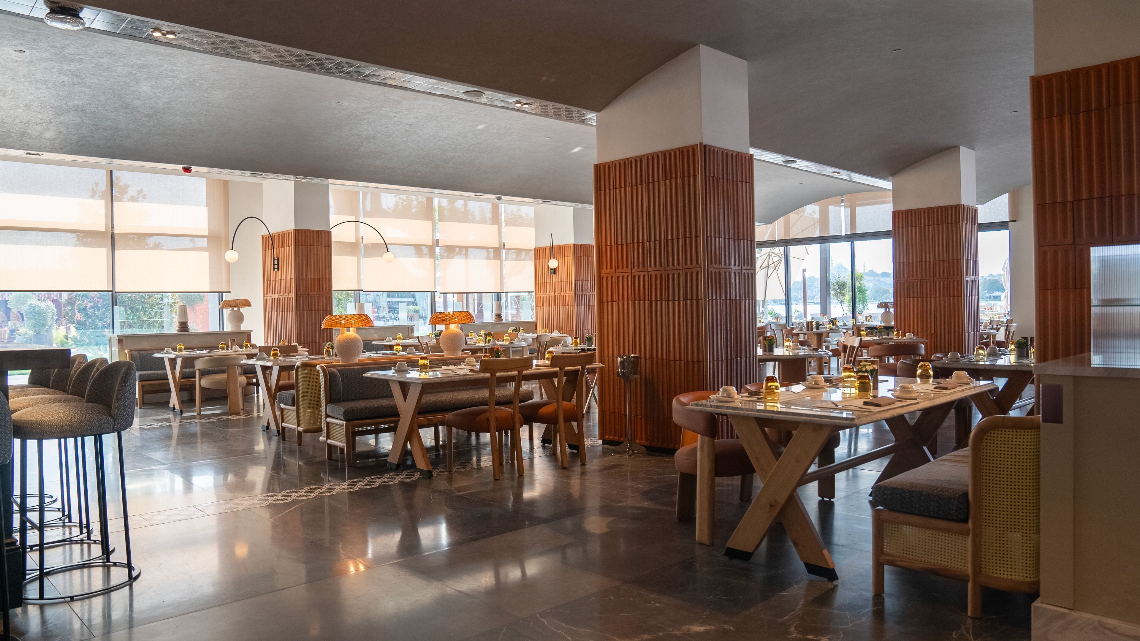 A spacious restaurant with high ceilings, large windows, and modern furnishings.