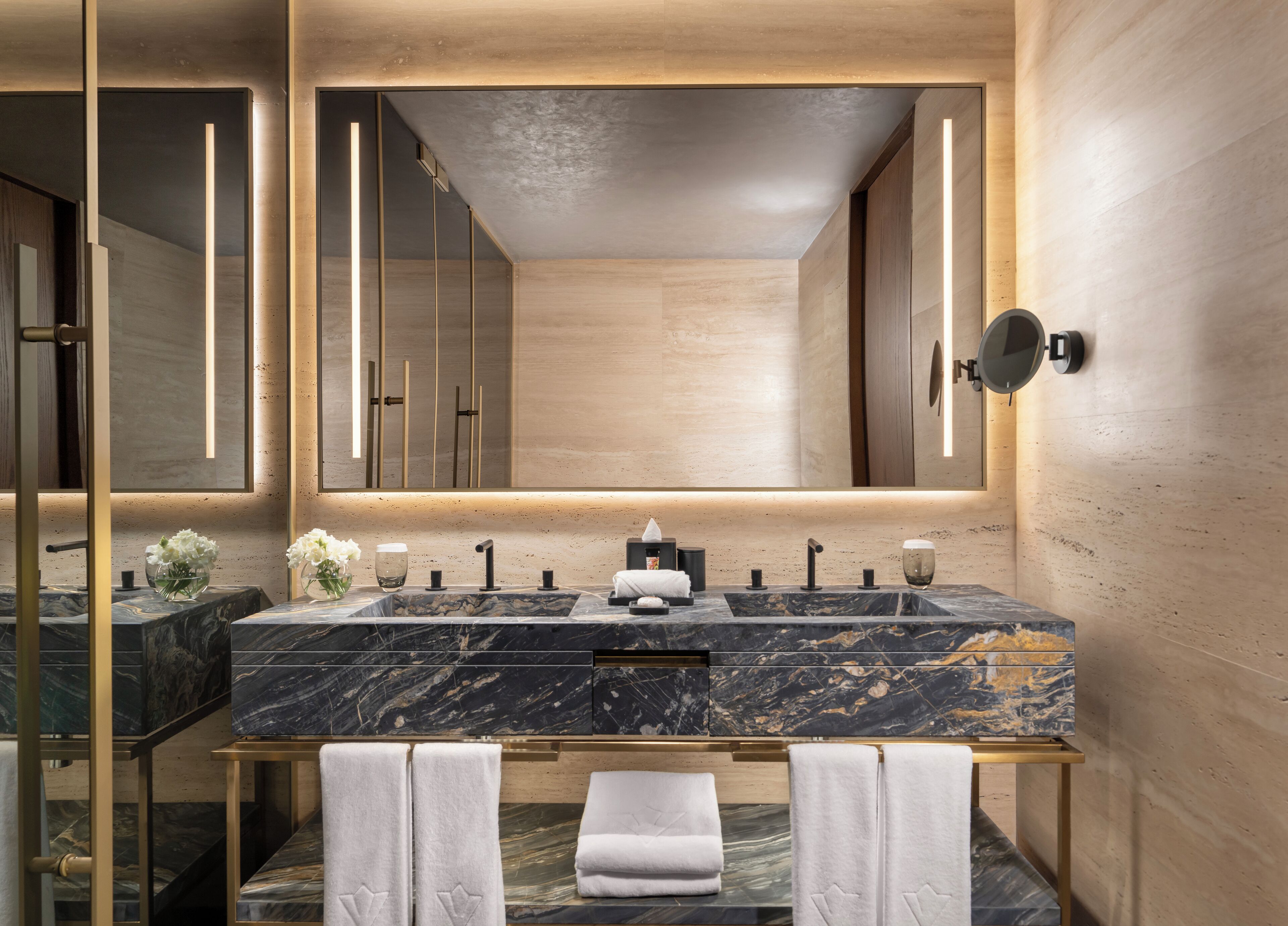 A modern bathroom with a large mirror, marble sink, and towel rack.