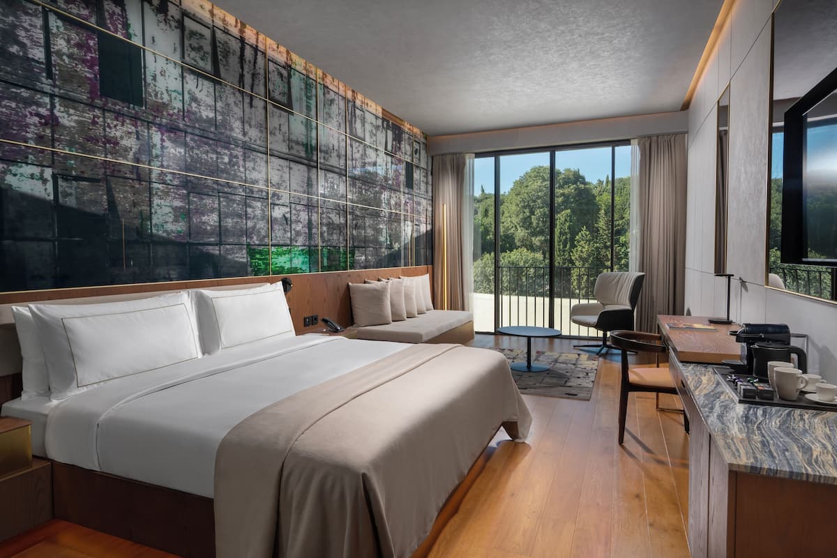 Una habitación de hotel moderna con una cama grande, un escritorio y vistas al exterior.