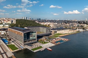 A waterfront hotel with modern architecture, a pool area, and a view of the city skyline. - Rixos Tersane Istanbul (Istanbul)