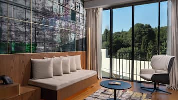 Una sala de estar moderna con un sofá, una silla, una mesa de centro y un ventanal con vistas a árboles.