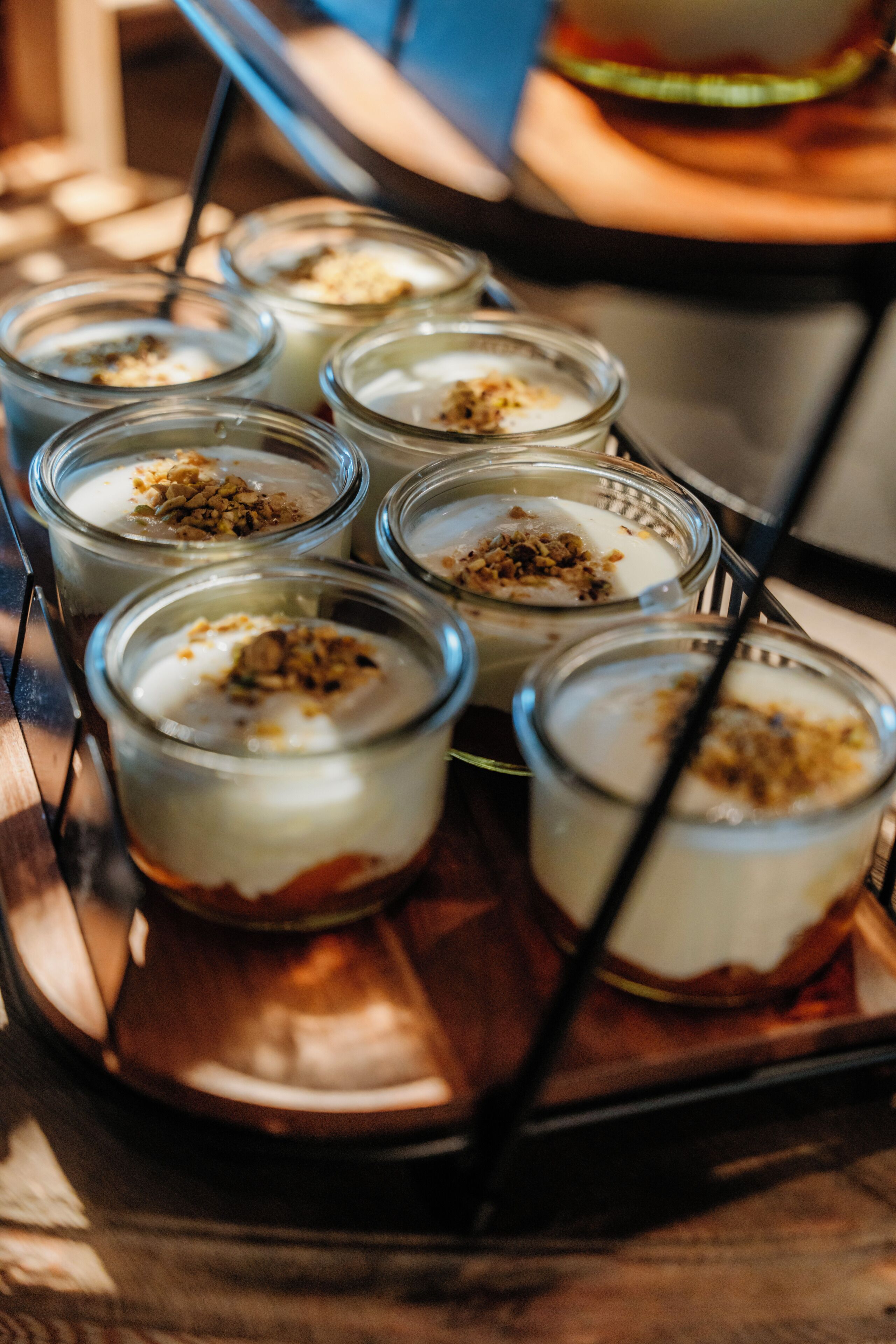 En bakke med dessertglas, med lagdelt dessert og topping, placeret på en træoverflade.